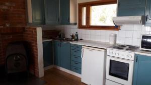 a kitchen with blue cabinets and a white stove top oven at Mellangårds stugor - Stockstugan in Föglö