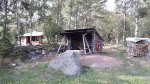a cabin in the woods with a pile of wood at Mellangårds stugor - Stockstugan in Föglö