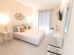 a white bedroom with a bed and a television at Akrogiali in Skala