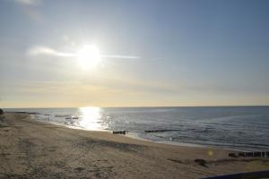 a beach with the sun shining on the water w obiekcie Apartamenty Danka w Gąskach