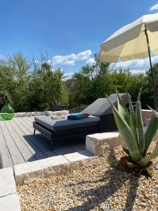 un patio con cama, sombrilla y cactus en Gemütliche Ferienwohnung mit Pool bei Jena, en Kahla