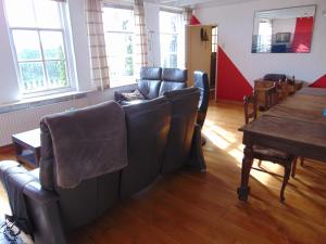 a living room with a couch and a table and windows at Polderhuis voor 8-10 personen aan zee in Nieuwvliet