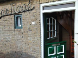 a brick building with a green door and a window at Polderhuis voor 8-10 personen aan zee in Nieuwvliet