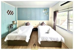 two beds in a room with blue walls at Hooman Hostel in Chiang Mai