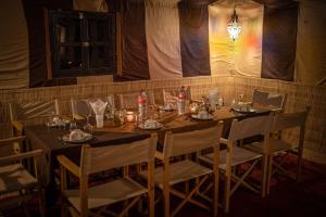 uma sala de jantar com uma mesa com cadeiras e uma luz em Desert Luxury Camp em M'hamid