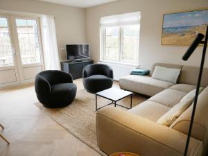 a living room with a couch and two chairs at Villa Donax in Sint Maartensvlotbrug