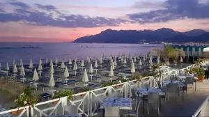 een groep tafels en witte parasols op een strand bij SEA4USALERNO seafront in Salerno