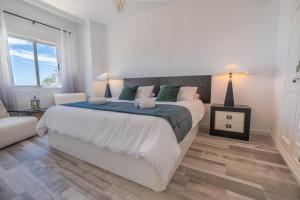 Un dormitorio blanco con una cama grande y una silla. en Panamanian Blue Sea View Flat, en La Herradura