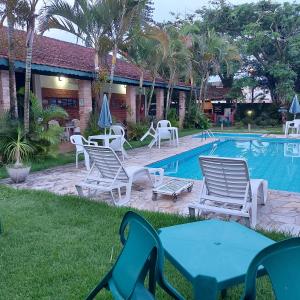 a group of chairs and tables next to a swimming pool at Pousada Chateau Sophie in Itanhaém