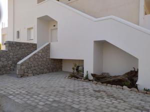 a staircase leading up to a white building with a stone wall at Estia - Brand new apartment in Ermioni Village in Ermioni