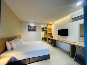 a bedroom with a bed and a desk with a television at AreNice Boutique Hotel in Surat Thani