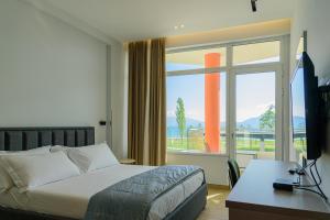 a bedroom with a bed and a desk and a window at Palm Side Hotel in Vlorë