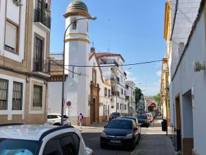 a street with cars parked in front of a lighthouse at Acogedor apartamento en semisótano con patio y cerca de la Plaza de España in Seville