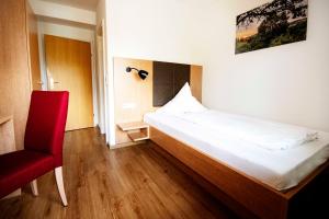 a bedroom with a bed and a red chair at Landhotel Graf in Schliengen