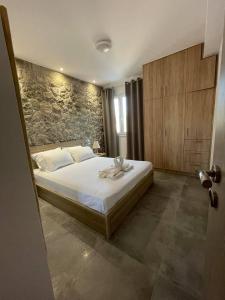 Armonia - Brand new apartment in Ermioni Village في إرميوني: غرفة نوم بسرير وجدار حجري