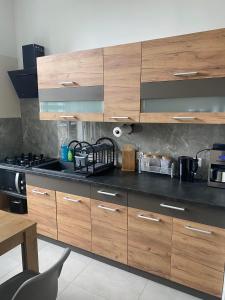 une cuisine avec des placards en bois et un comptoir noir dans l'établissement Willa Andersa, à Ruciane-Nida