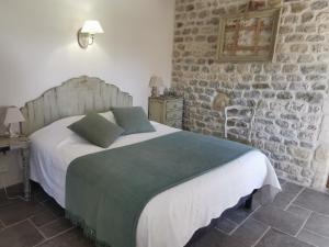 um quarto com uma cama e uma parede de pedra em La petite plaine em Clansayes