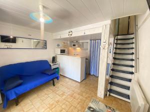 a living room with a blue couch and a kitchen at La Maison Bleue in Gruissan
