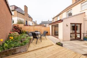 une terrasse en bois avec une table et des chaises. dans l'établissement Pipeland Pad - 3 Bed - Parking - Garden, à St Andrews