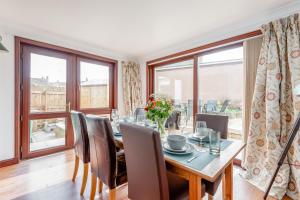 a dining room with a table and chairs and windows at Pipeland Pad - 3 Bed - Parking - Garden in St Andrews