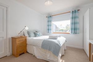 a white bedroom with a bed and a window at Pipeland Pad - 3 Bed - Parking - Garden in St Andrews
