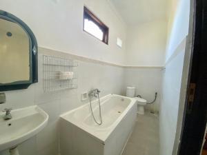 a white bathroom with a tub and a sink at Pondok Mimba in Padangbai