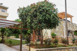a tree with red flowers in front of a building at Ferienhaus Kreta Sonnenschein in Plataniás