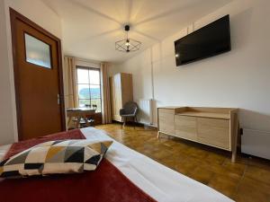 a bedroom with a bed and a flat screen tv at Auberge du Point Sublime in Rougon