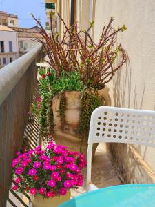 un balcón con flores, una mesa y una silla en Fortuna Guest House, en Siracusa