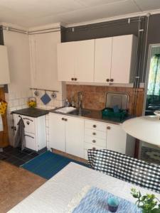 a small kitchen with white cabinets and a sink at Stavred-gården in Bjärtrå