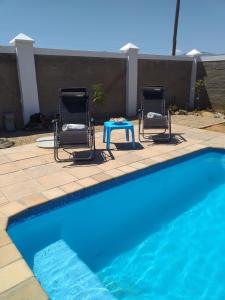 two chairs and a table next to a swimming pool at Karoo Magic in Calitzdorp