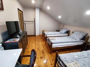 um quarto com 3 camas e uma televisão de ecrã plano em WILLA JUTRZENKA em Ostrowiec Świetokrzyski