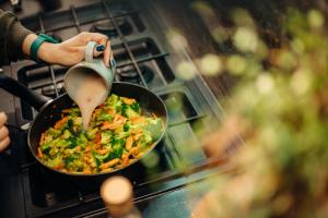 eine Person, die Essen in einer Pfanne auf einem Herd kocht in der Unterkunft Gęsi Zakręt in Ustrzyki Dolne + 17 Fotos