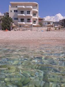 een gebouw op het strand met rotsen in het water bij Magic Ionian Apartments & Rooms in Himare