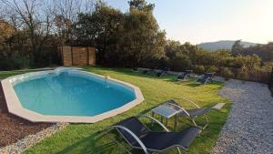 - une piscine entourée de chaises dans l'herbe dans l'établissement La Villa de Luna, à Vals-les-Bains