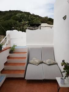 a balcony with a couch and stairs on a house at Le Case dei Pescatori - Casetta Faraglioni in Ponza