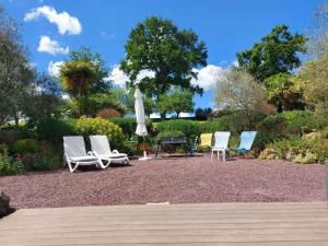 a group of chairs and an umbrella in a yard at Havre de paix et jardin tropical. Chambre privée in Le Rheu