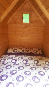 a bed in a log cabin with a window at Rafting Kamp Brijeg in Kružac