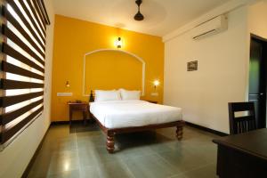 ein Schlafzimmer mit einem weißen Bett und einer gelben Wand in der Unterkunft THE SUNSET BAY in Fort Kochi