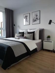 a bedroom with a large bed with black and white sheets at Apartament 150 Zaspa VVita z ogrodem i tarasem in Gdańsk