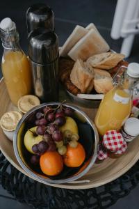 a tray with a bowl of fruit and bread and juice at L'intimiste in Longeville-sur-Mer