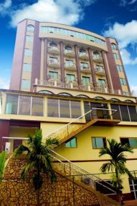 un grand bâtiment avec des palmiers devant lui dans l'établissement FELICIA HOTEL YAOUNDE, à Yaoundé