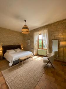 a bedroom with a large bed and a chair at Les Courtines - Appartement de caractère à la Roque-Gageac - Les Chênes Verts in La Roque-Gageac