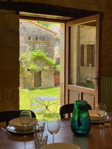 une table en bois avec un vase vert au-dessus dans l'établissement Les Courtines - Appartement de caractère à la Roque-Gageac - Les Chênes Verts, à La Roque-Gageac