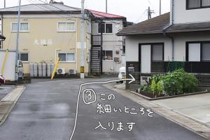 una strada con un cartello in mezzo alla strada di コトのアート研究所 a Ishinomaki