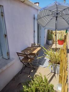 une terrasse avec une table et un parasol dans l'établissement Maison de pêcheur à 2 pas de la mer (200m), à Bretignolles-sur-Mer