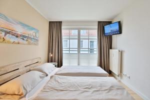 a bedroom with two beds and a tv on the wall at Haus Seerose Seerose II Appartement 14 in Scharbeutz
