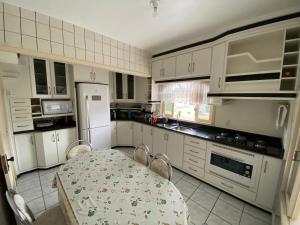 uma cozinha com uma mesa e cadeiras e um frigorífico branco em Suíte Residencial320 - Timbó em Timbó