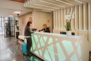 deux femmes debout à un comptoir d'accueil dans un bureau dans l'établissement Arya Stadium Hotel, à Barcelone