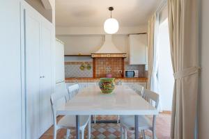 a kitchen with a white table with chairs and a vase on it at CATHENA HOLIDAY CEFALU in Cefalù